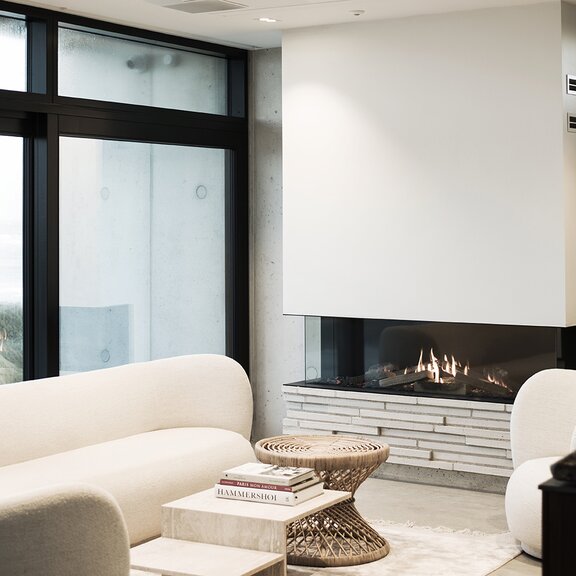 Gas-Kamineinsatz VISIO 160 mit dreiseitigem Glas, weisser Wand und moderner Wohnraum
