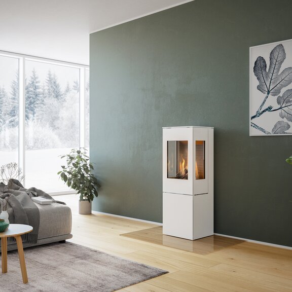 Gas-Kaminofen NEXO 120 in Weiss mit Stahltür und zwei Seitenfenstern vor grüner Wand in dekorativem Wohnraum