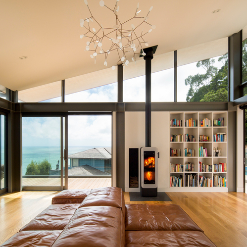 bionic fire EVO in Schwarz mit weisser Vollglas-Feuerraumtür Holz-Kaminofen bionic fire EVO in der Farbe Schwarz mit weisser Vollglas-Feuerraumtüre im Wohnzimmer am Meer